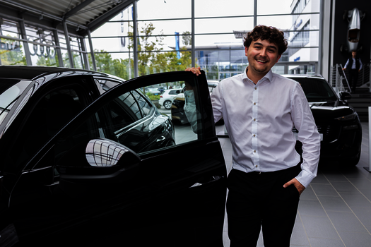 Junger Mann steht im Showroom des Autohauses
